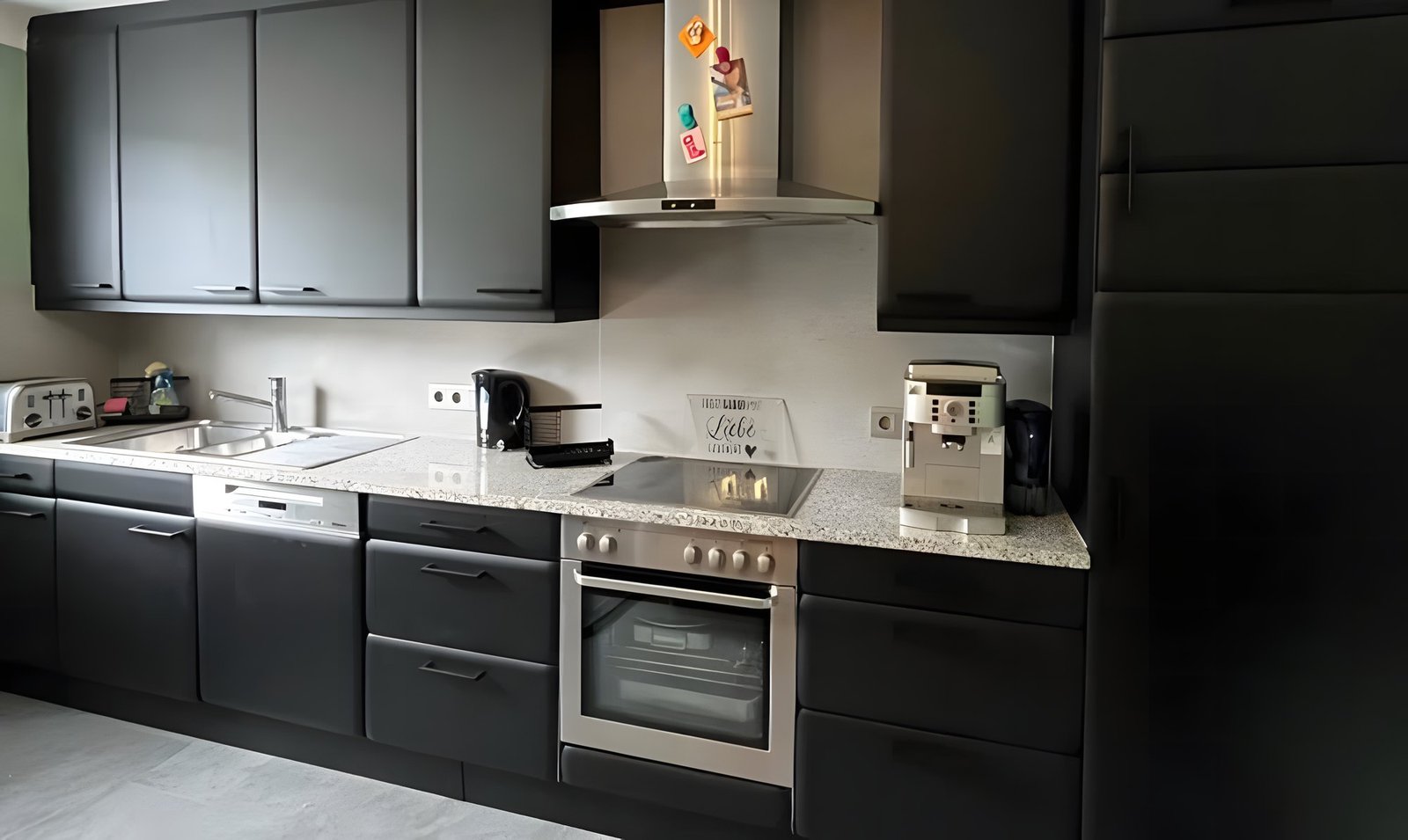 Après : la même cuisine aux façades noir mat, crédence unie gris clair, plan de travail en granit conservé.
