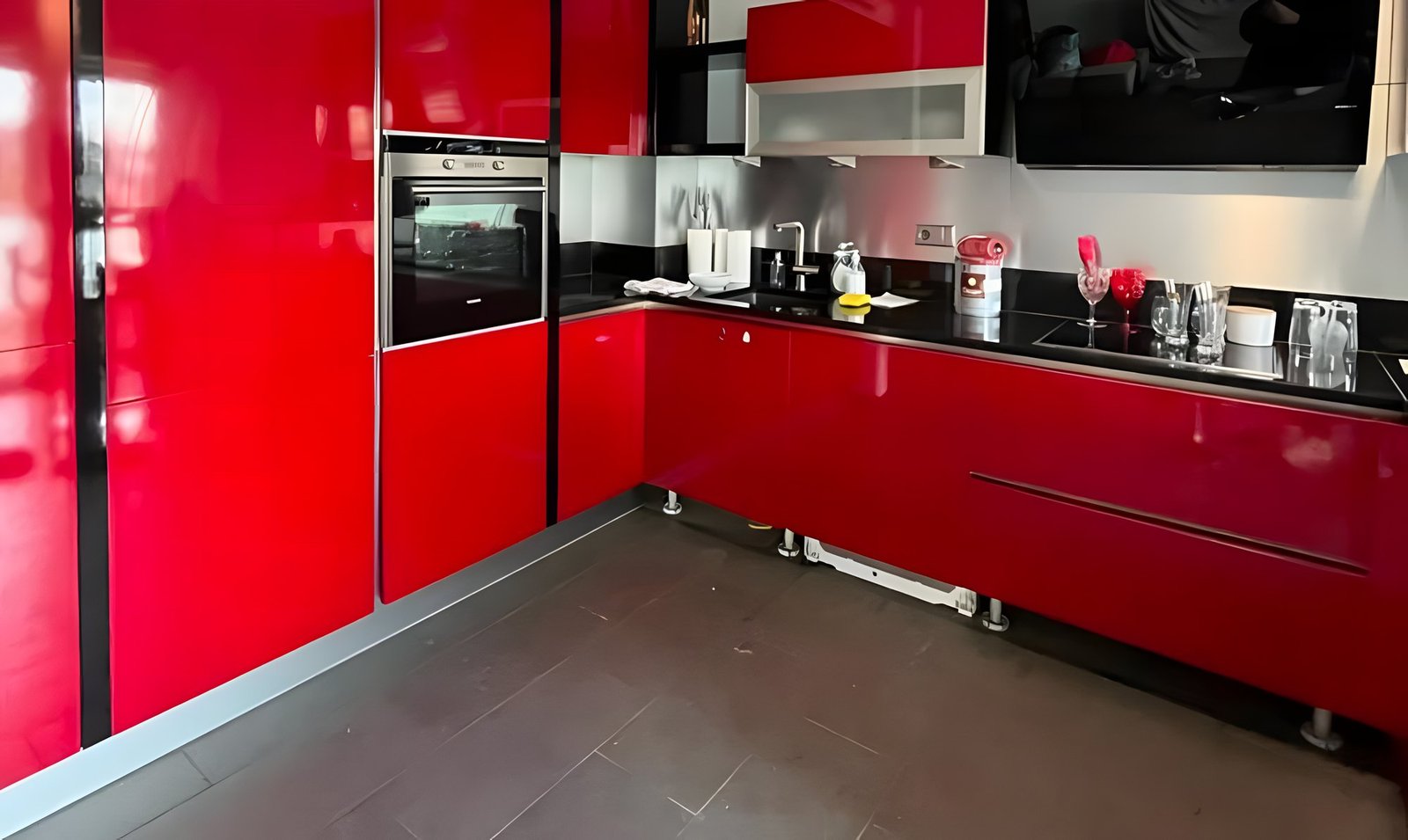 Avant : cuisine d'angle aux façades rouge vif laqué brillant et plan de travail noir.