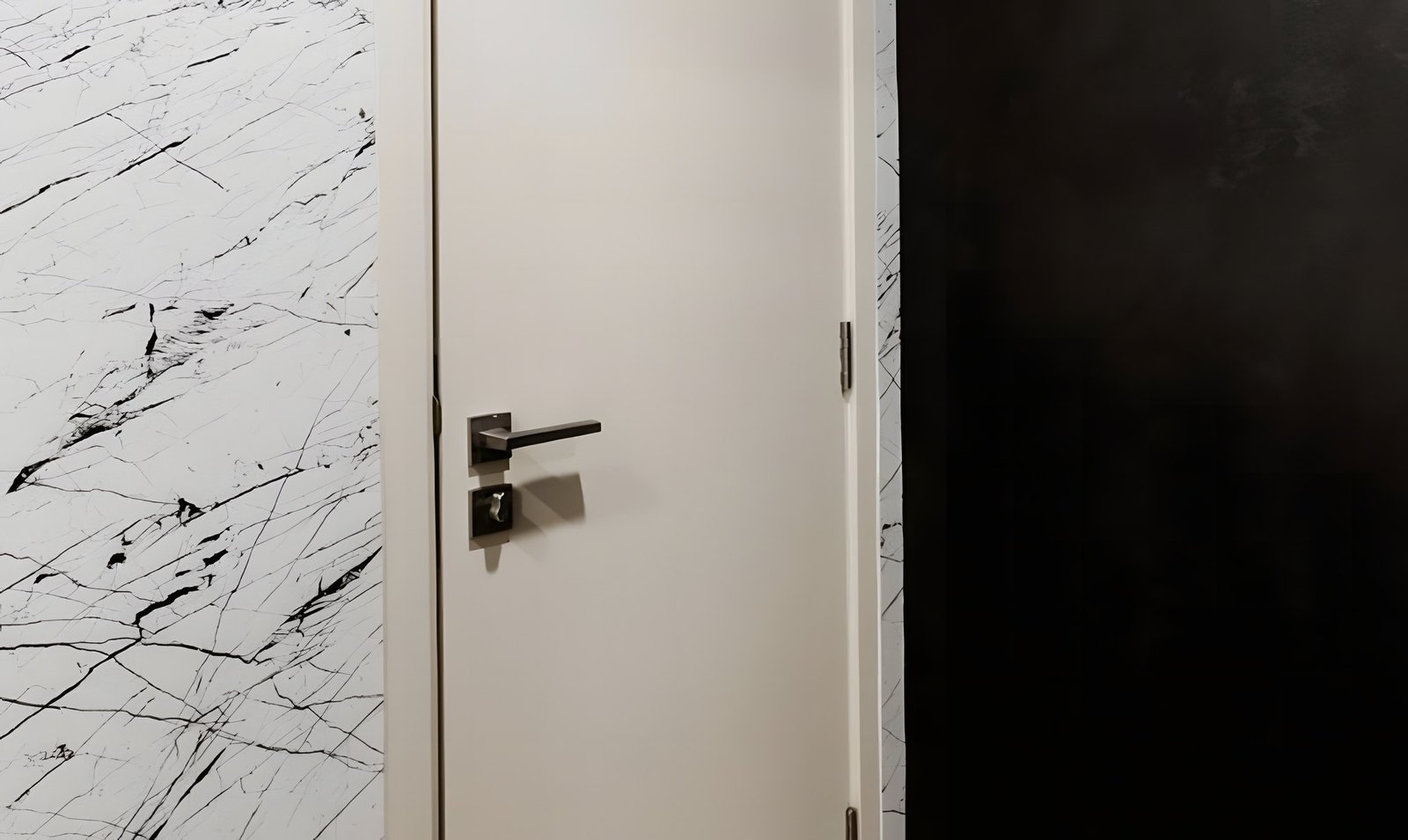 Après : la même porte en blanc cassé mat, entre un mur aspect marbre blanc veiné de noir et un mur noir.