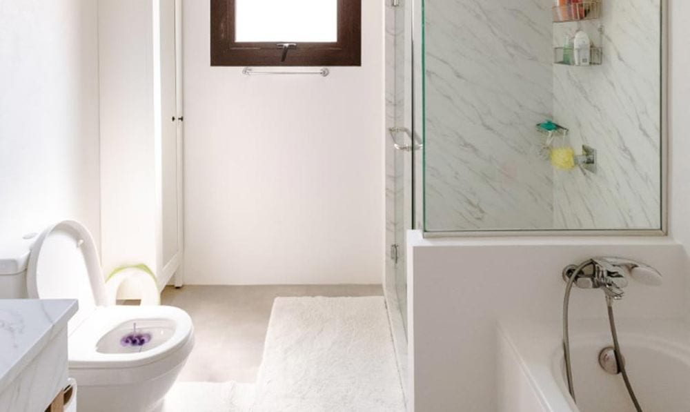 Après : la même salle de bain aux murs blancs, douche aspect marbre blanc veiné et plan vasque clair.